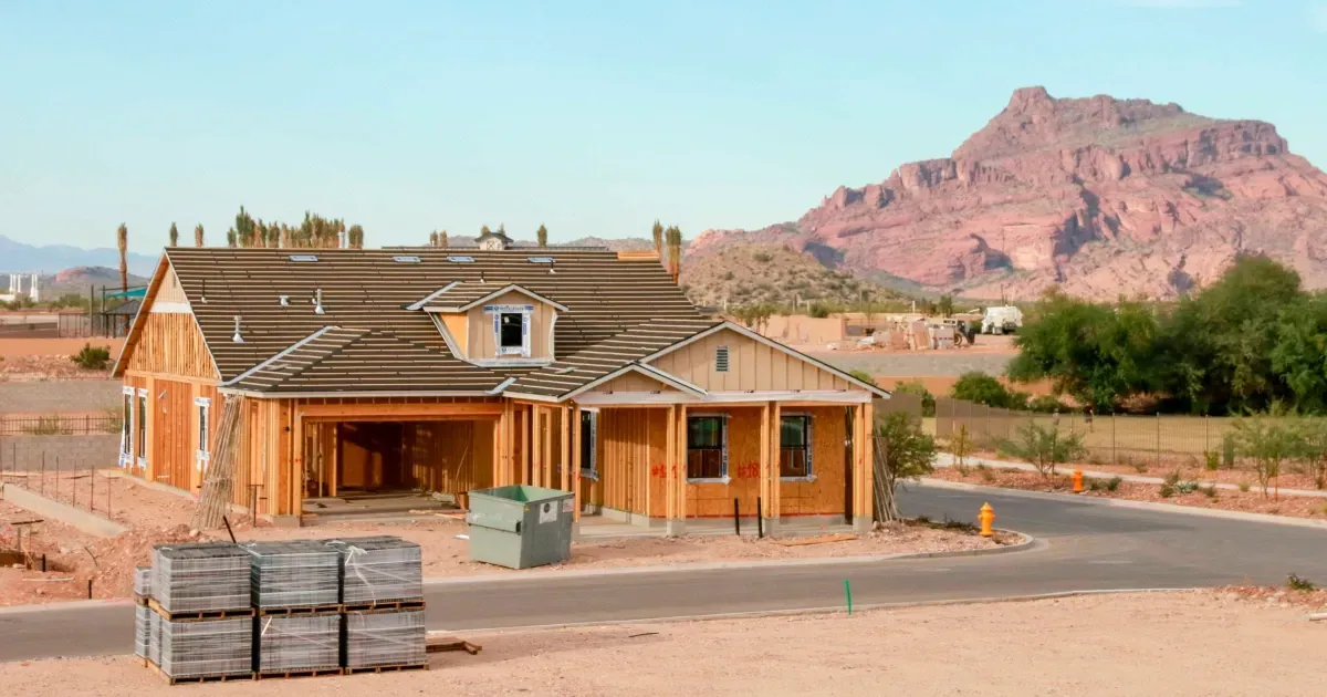 House under construction in arid setting with mountain in the background.