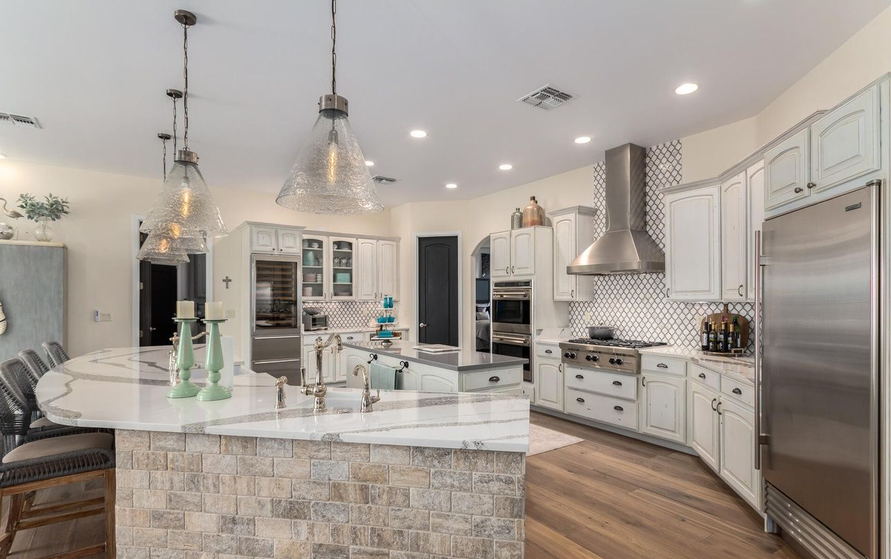 Spacious, modern kitchen with white cabinets, stainless steel appliances, and large island.