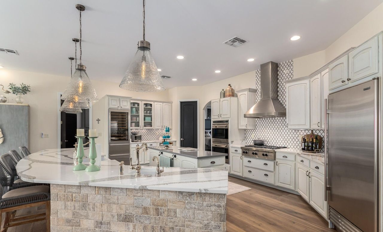 Spacious kitchen with white cabinets, stainless steel appliances, and a marble-topped island.