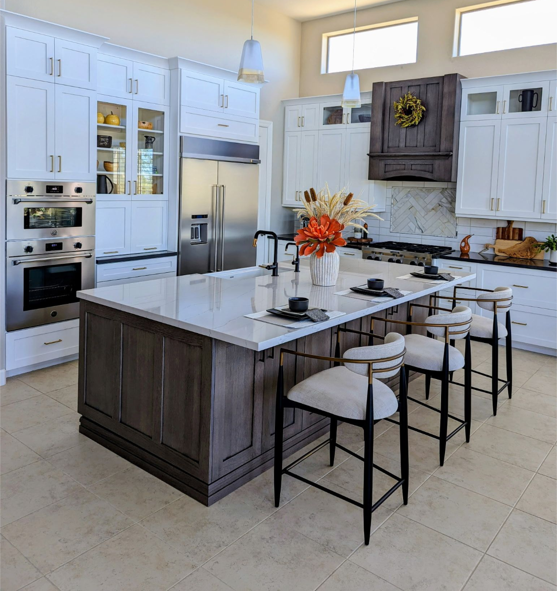 Spacious kitchen with white cabinets, dark island, stainless steel appliances, and bar stools.