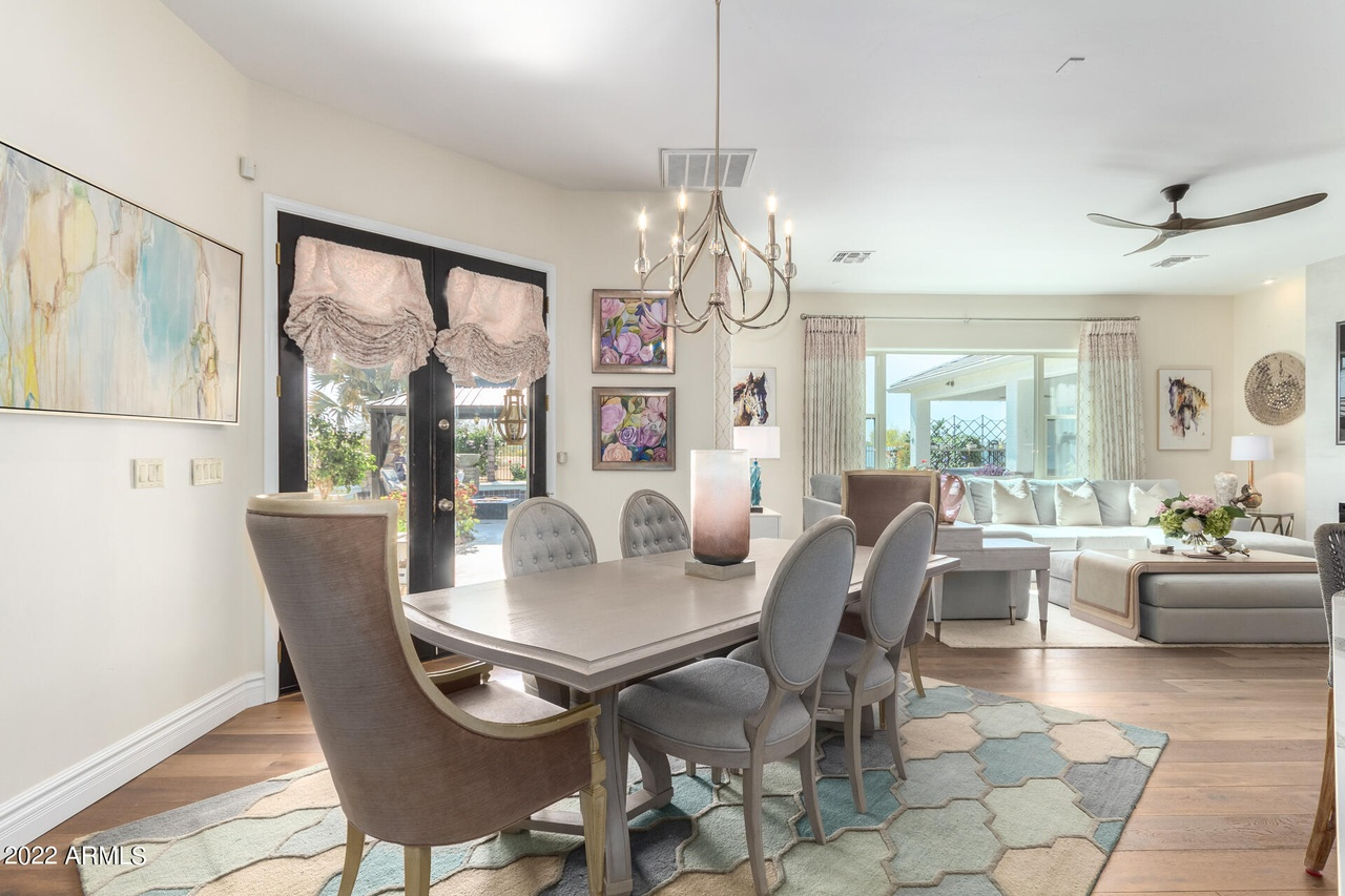 Elegant dining room with table, chairs, chandelier, and view to a living room.
