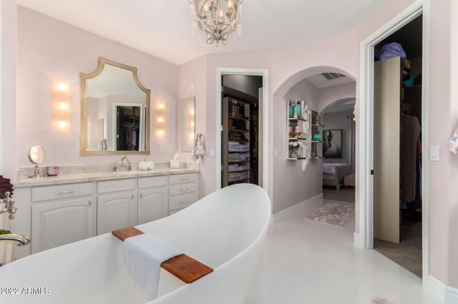 Elegant pink bathroom with a freestanding tub, vanity, and walk-in closet.