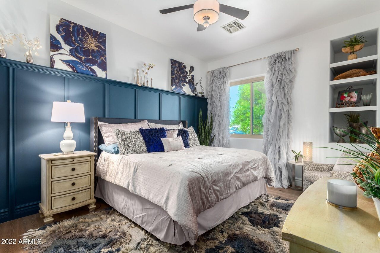 Bedroom with blue accent wall, bed, nightstand, rug, and built-in shelves.