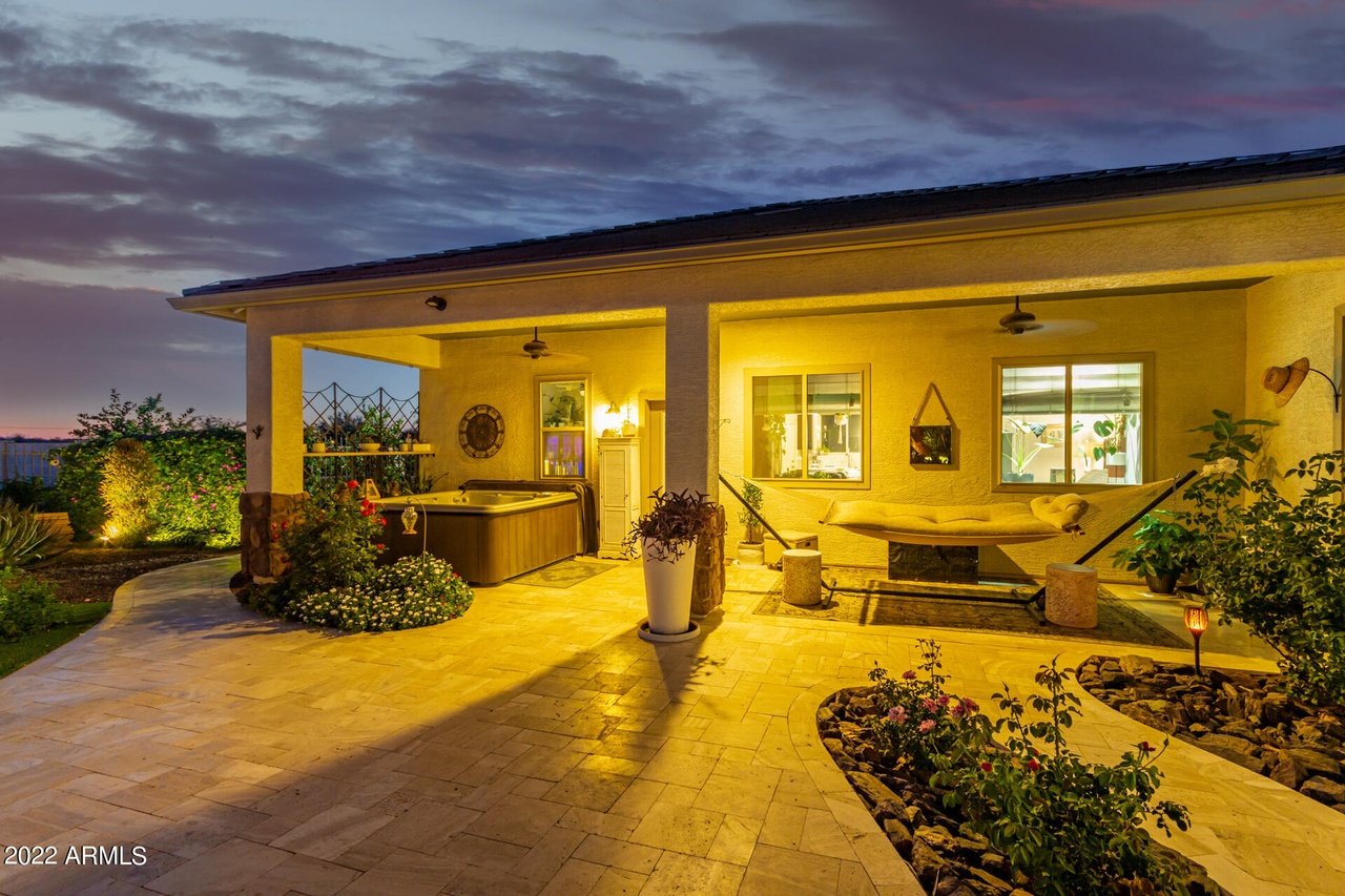 Back patio at dusk with hot tub, table, and plants.