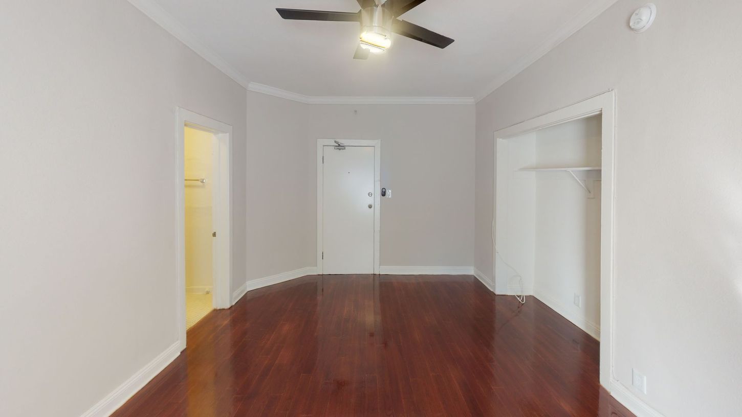 Empty room with hardwood floors, white walls, closet, and a ceiling fan.