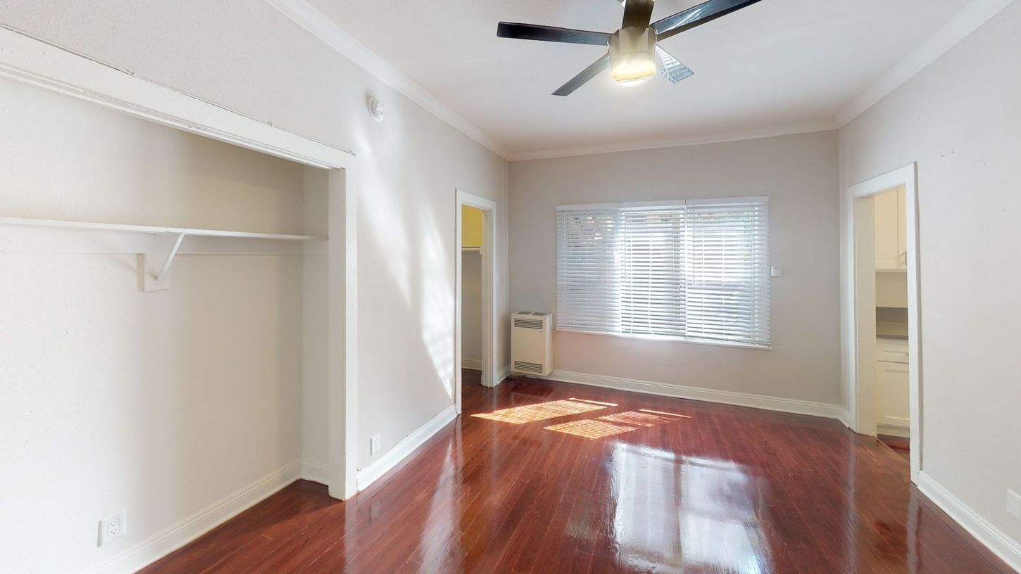 Empty room with wood floor, closet, window, and ceiling fan.