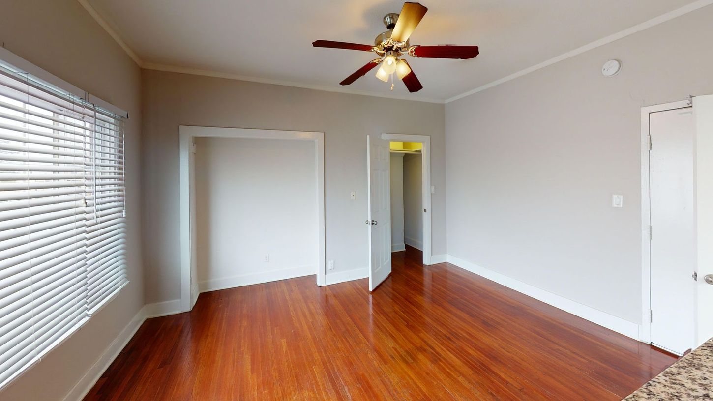 Empty room with hardwood floors, closet, window with blinds, and ceiling fan.