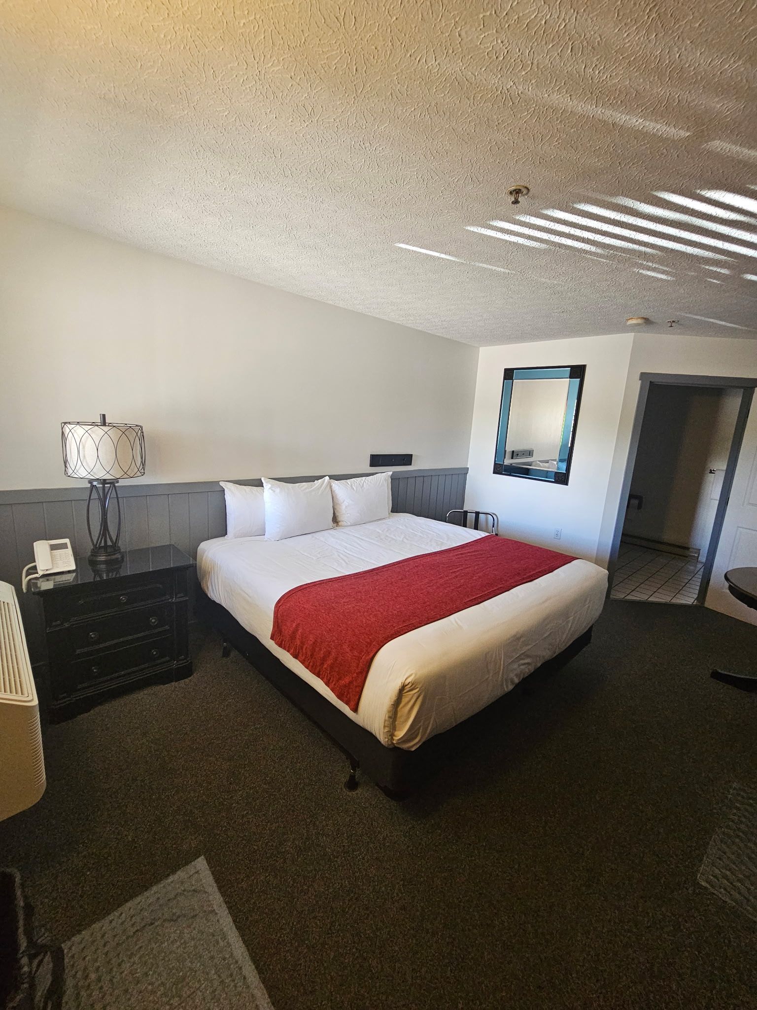 A hotel room with a king size bed and a mirror on the wall.