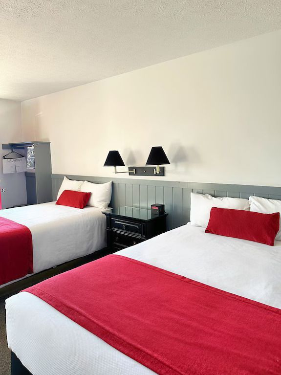 A hotel room with two beds and a red blanket