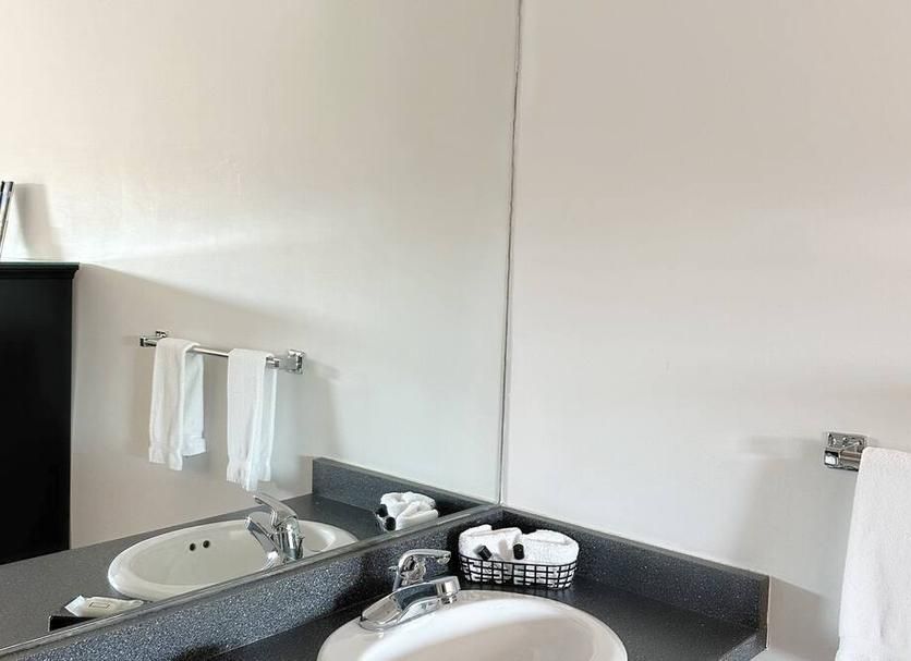 A bathroom with a sink , mirror and towels.