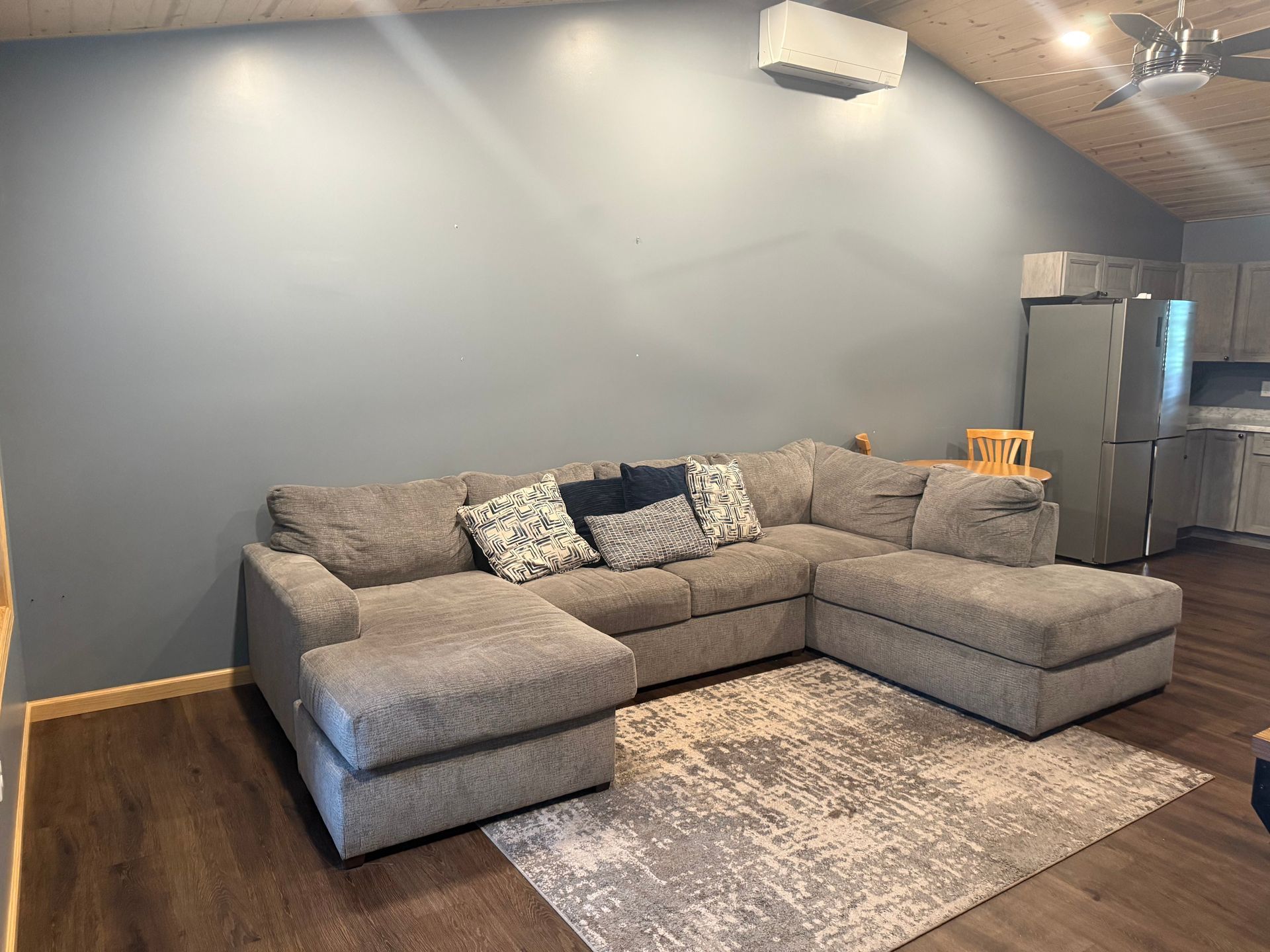 A living room with a large sectional couch and a rug.
