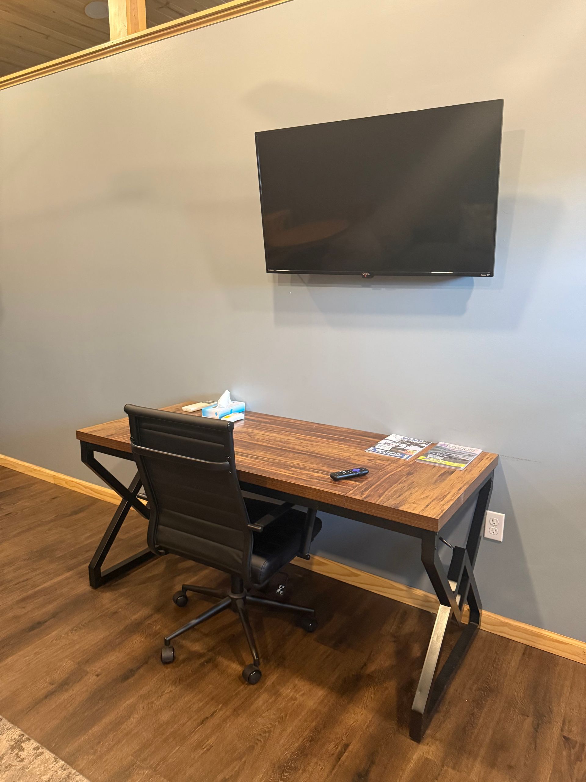 A desk with a chair and a flat screen tv mounted on the wall.