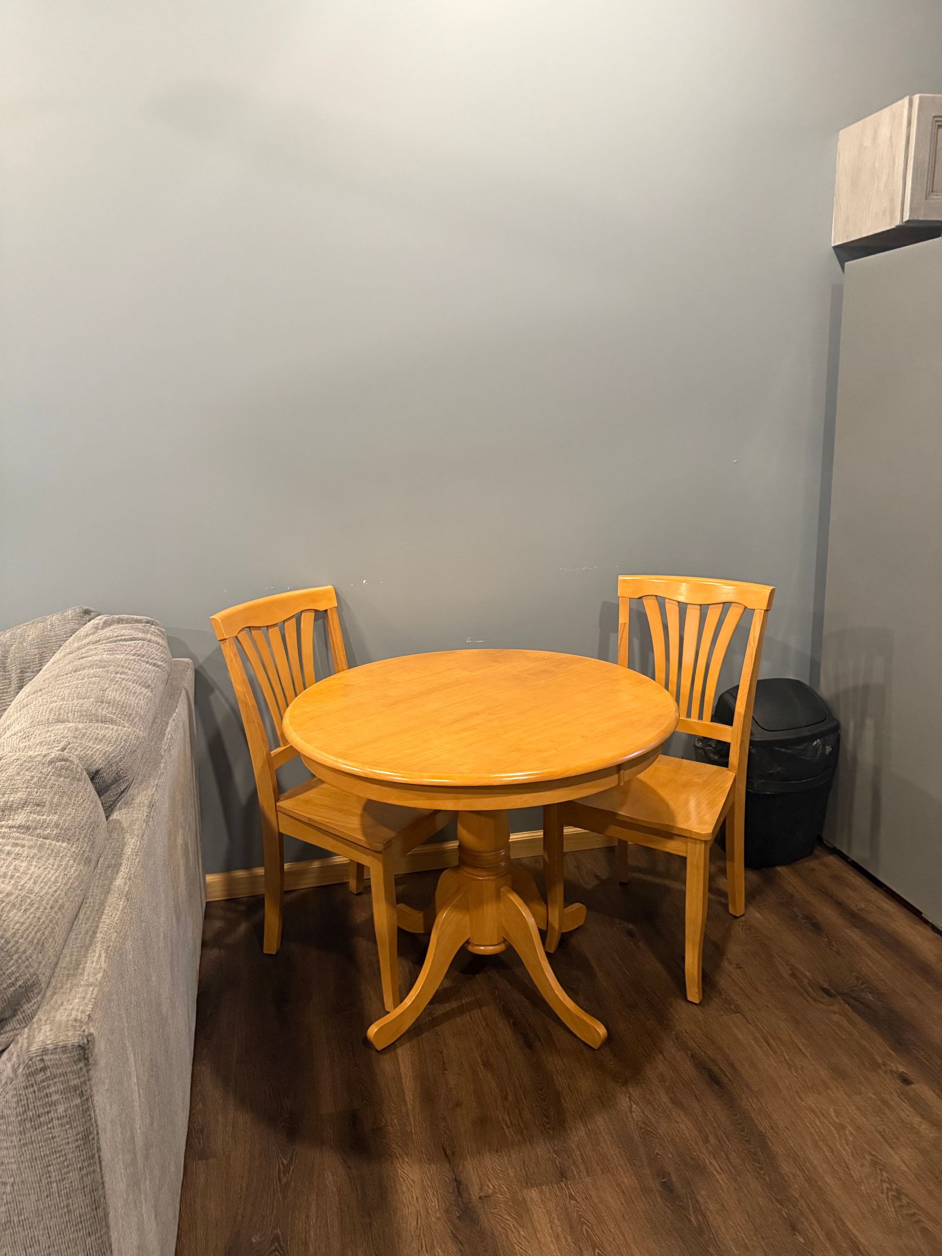 A small wooden table and chairs in a living room next to a couch.