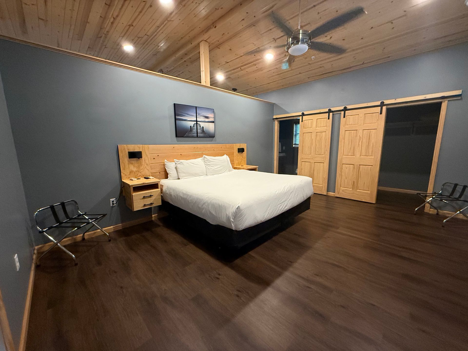 A hotel room with a king size bed , sliding barn doors and a ceiling fan.