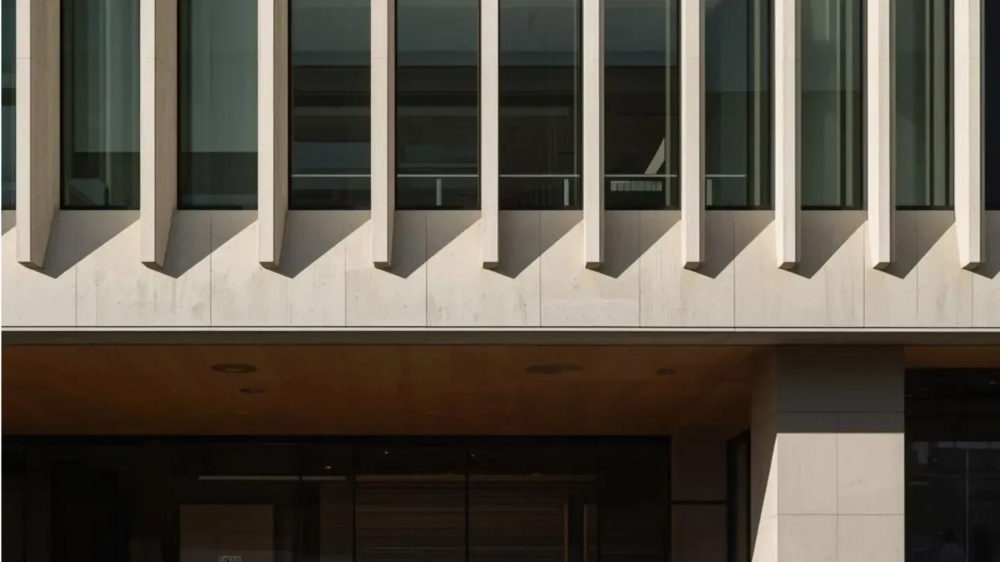 Modern building exterior with floor-to-ceiling glass windows and vertical light-colored stone fins.