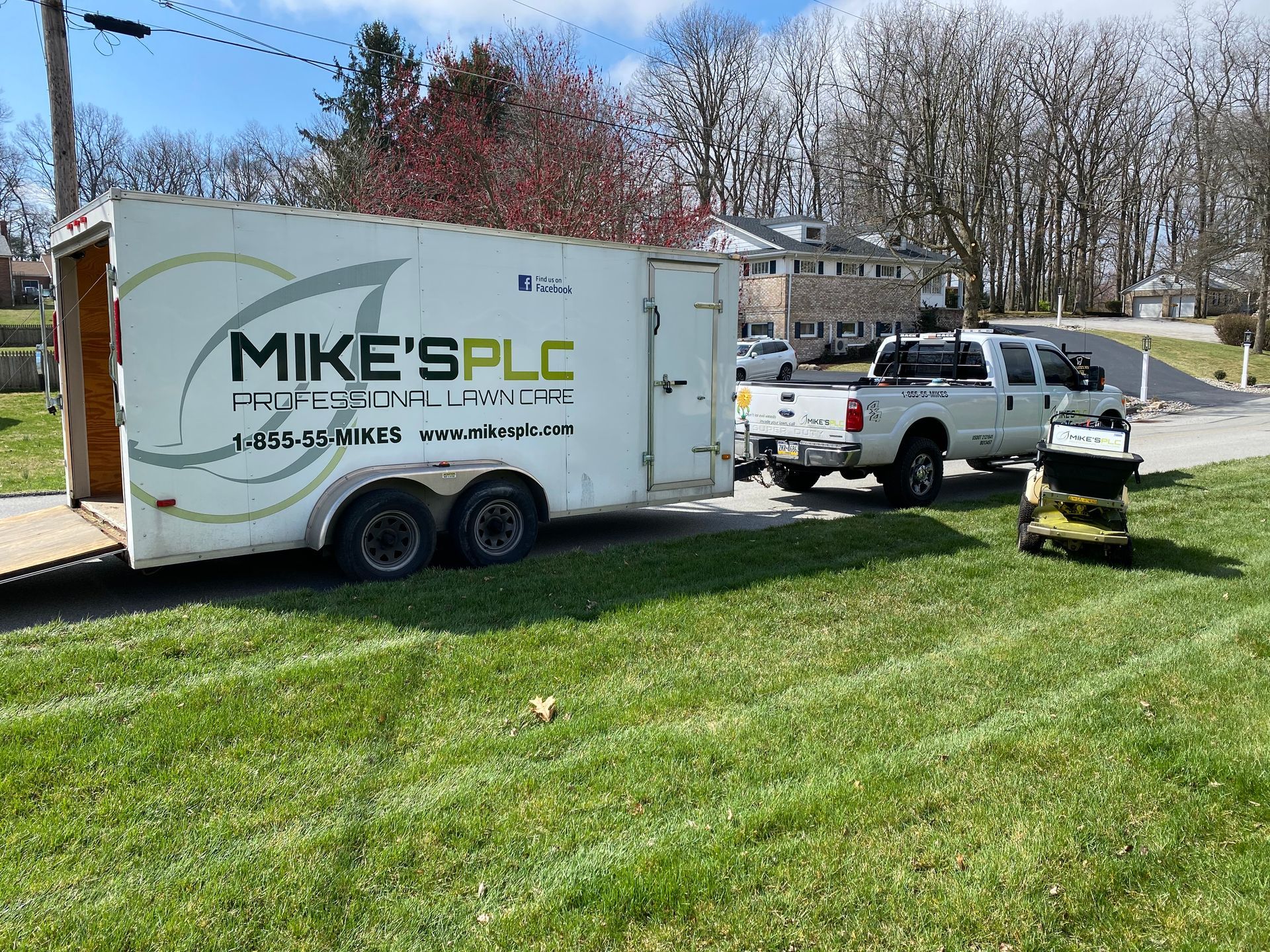 A truck is pulling a trailer with a lawn mower on it.