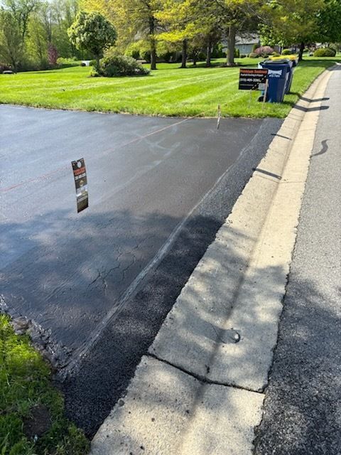 A driveway with a concrete curb and a grassy yard in the background.