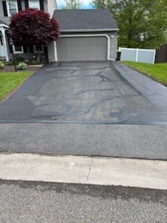 A driveway leading to a house with a tree in the middle of it.