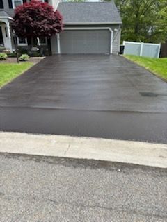 A driveway leading to a house with a garage and a tree.