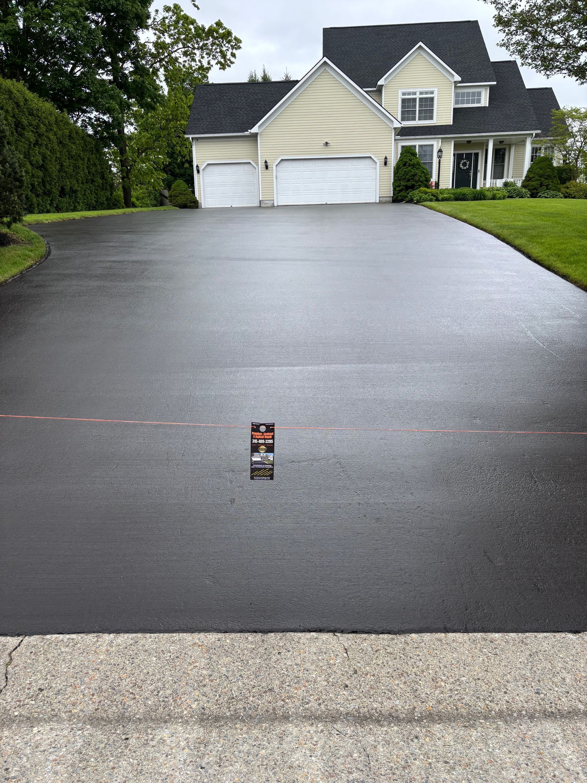 A black driveway with a yellow house in the background.