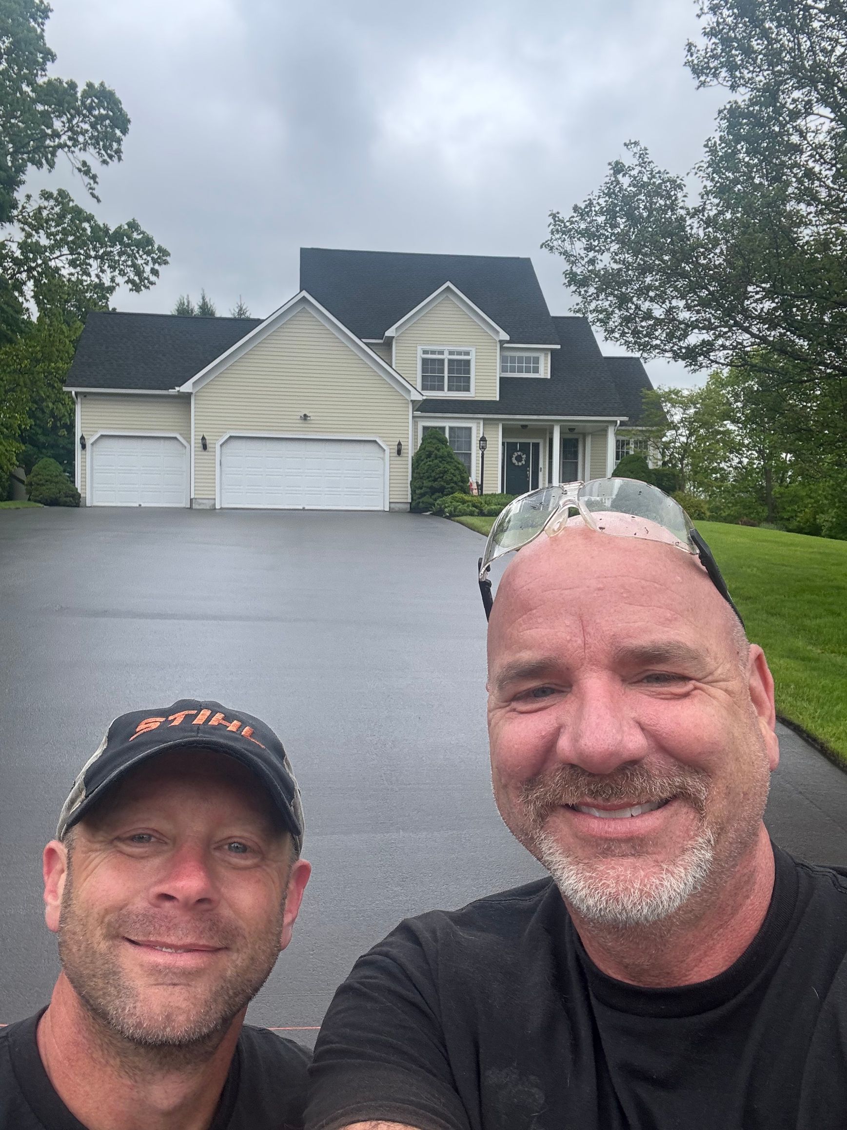 Two men are posing for a picture in front of a large house.