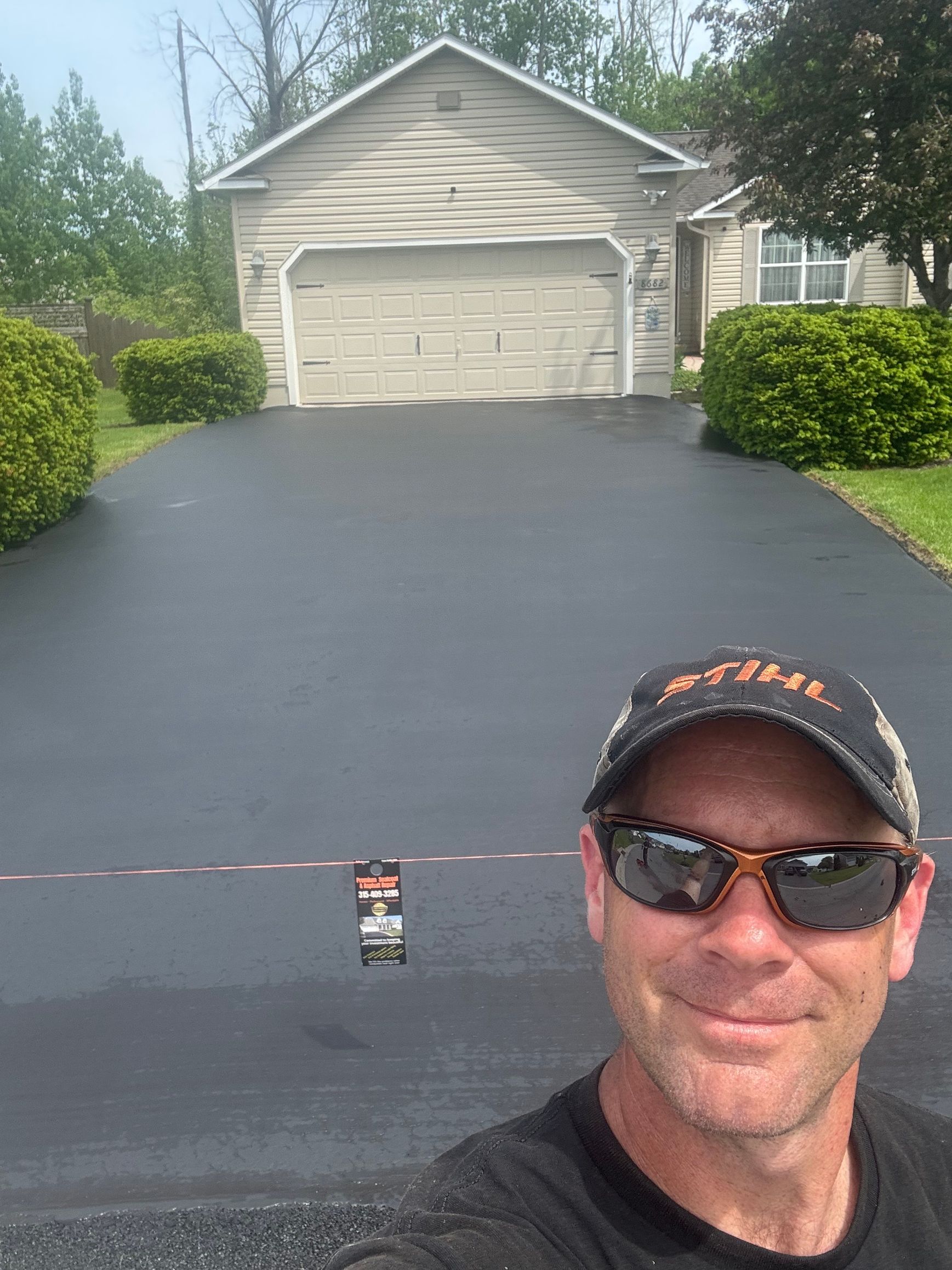 A man wearing sunglasses and a baseball cap is standing in front of a garage.