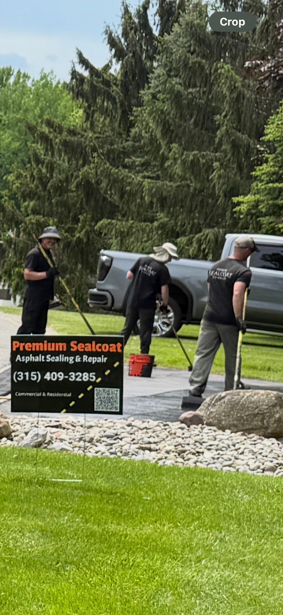 A group of men are cleaning a driveway next to a truck.