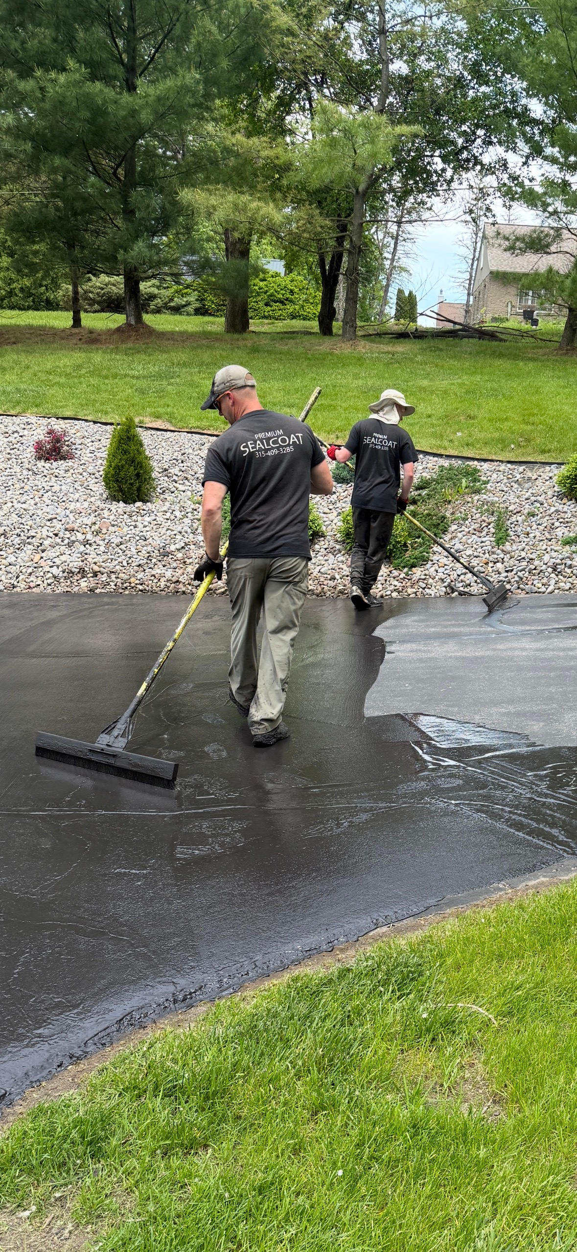 Two men are cleaning a driveway with a broom.