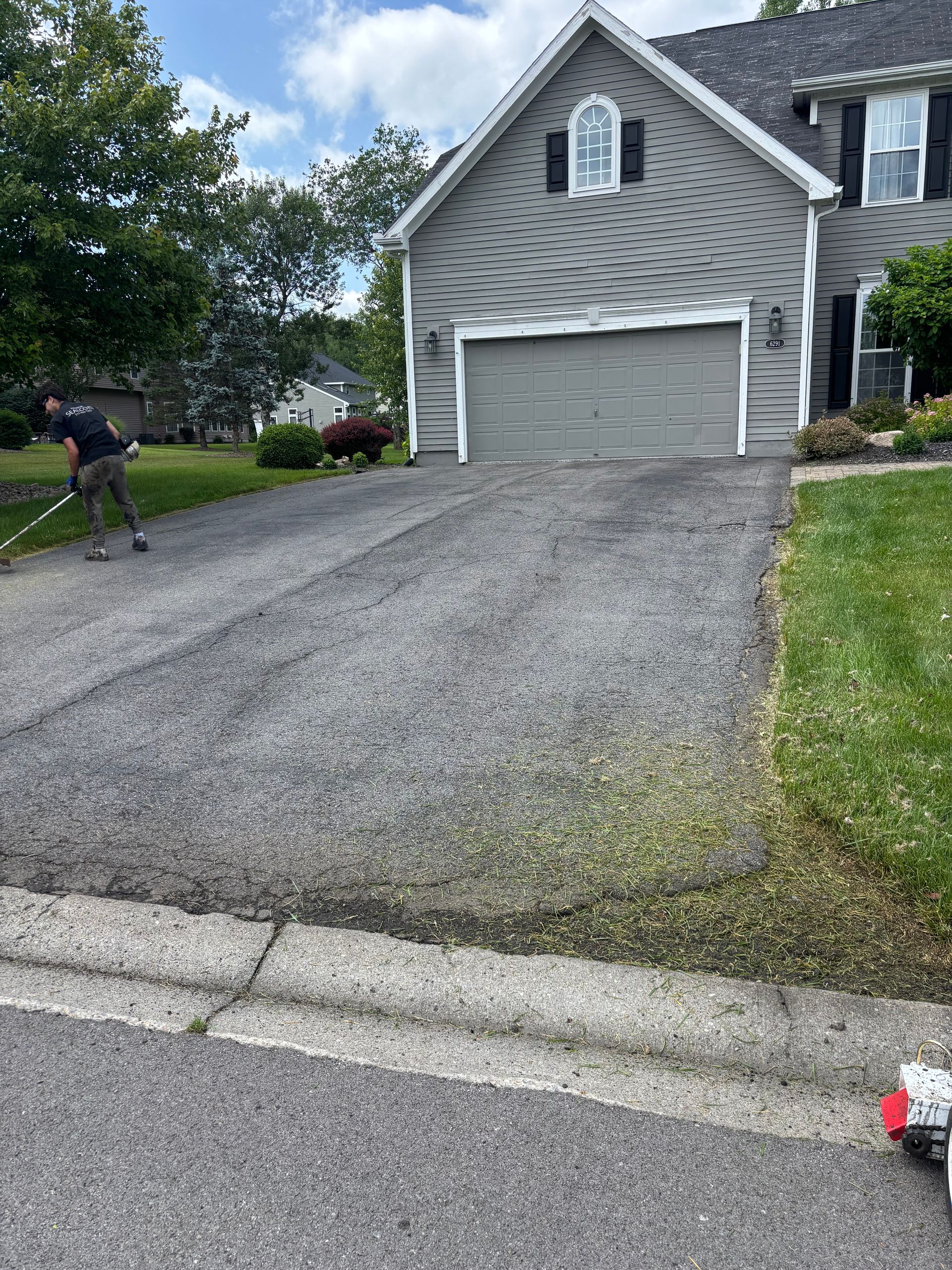 A lawn mower is sitting on the side of a road next to a house.