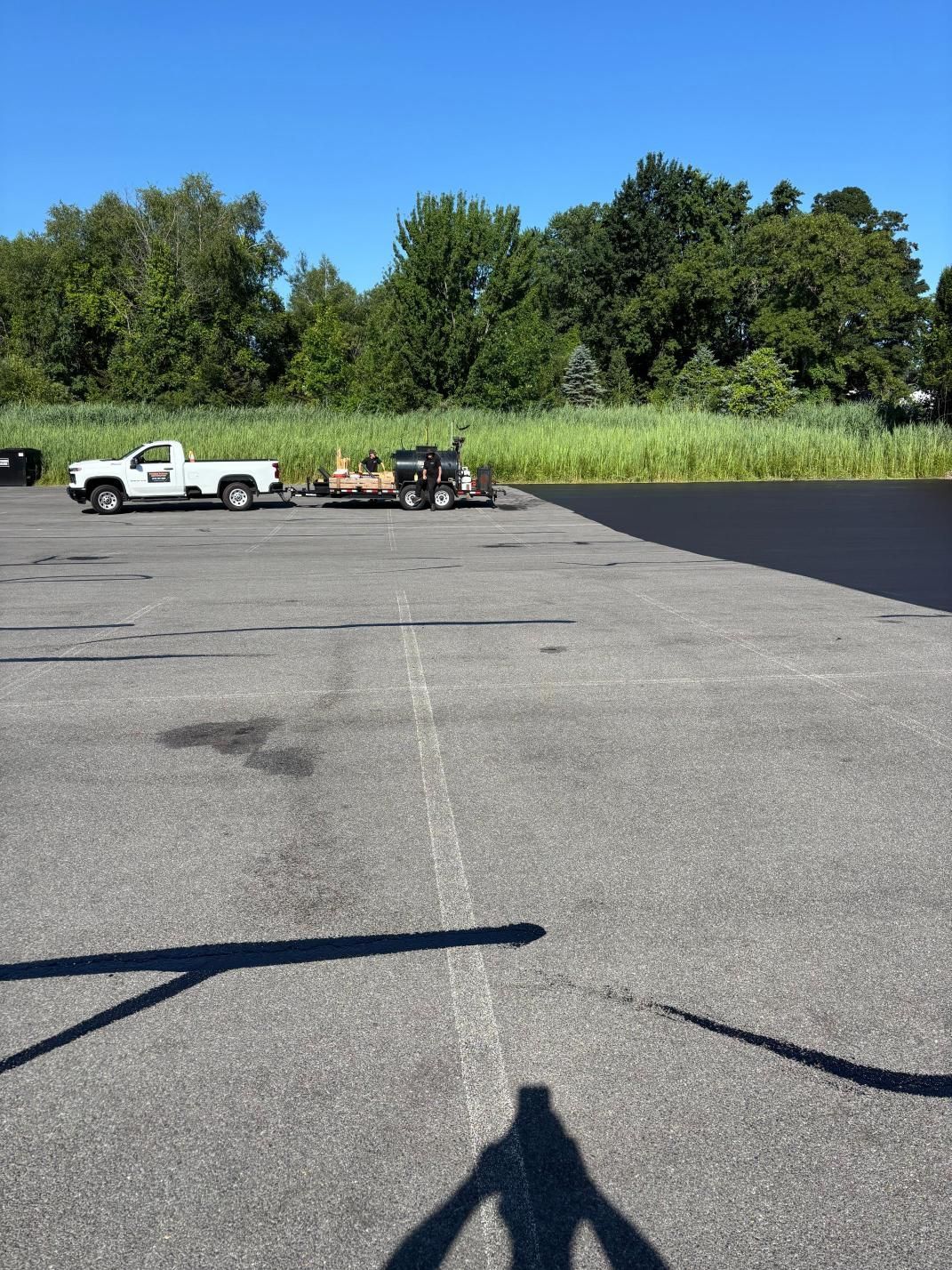 A white truck is parked in a parking lot next to a trailer.