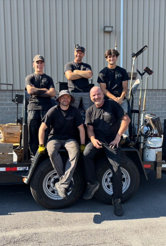 A group of men are posing for a picture while sitting on a trailer.