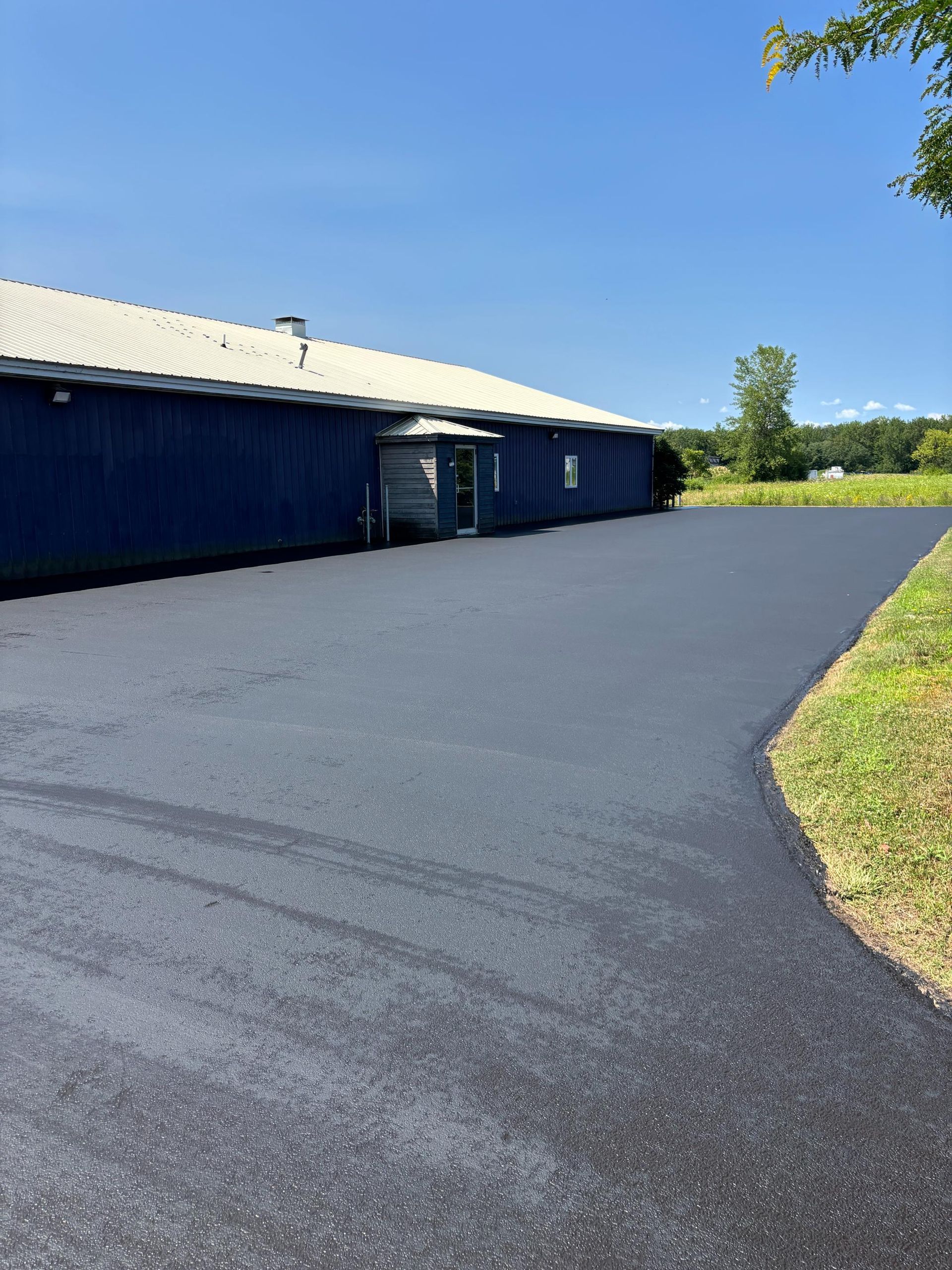 Blue building with a fresh asphalt driveway on a sunny day.