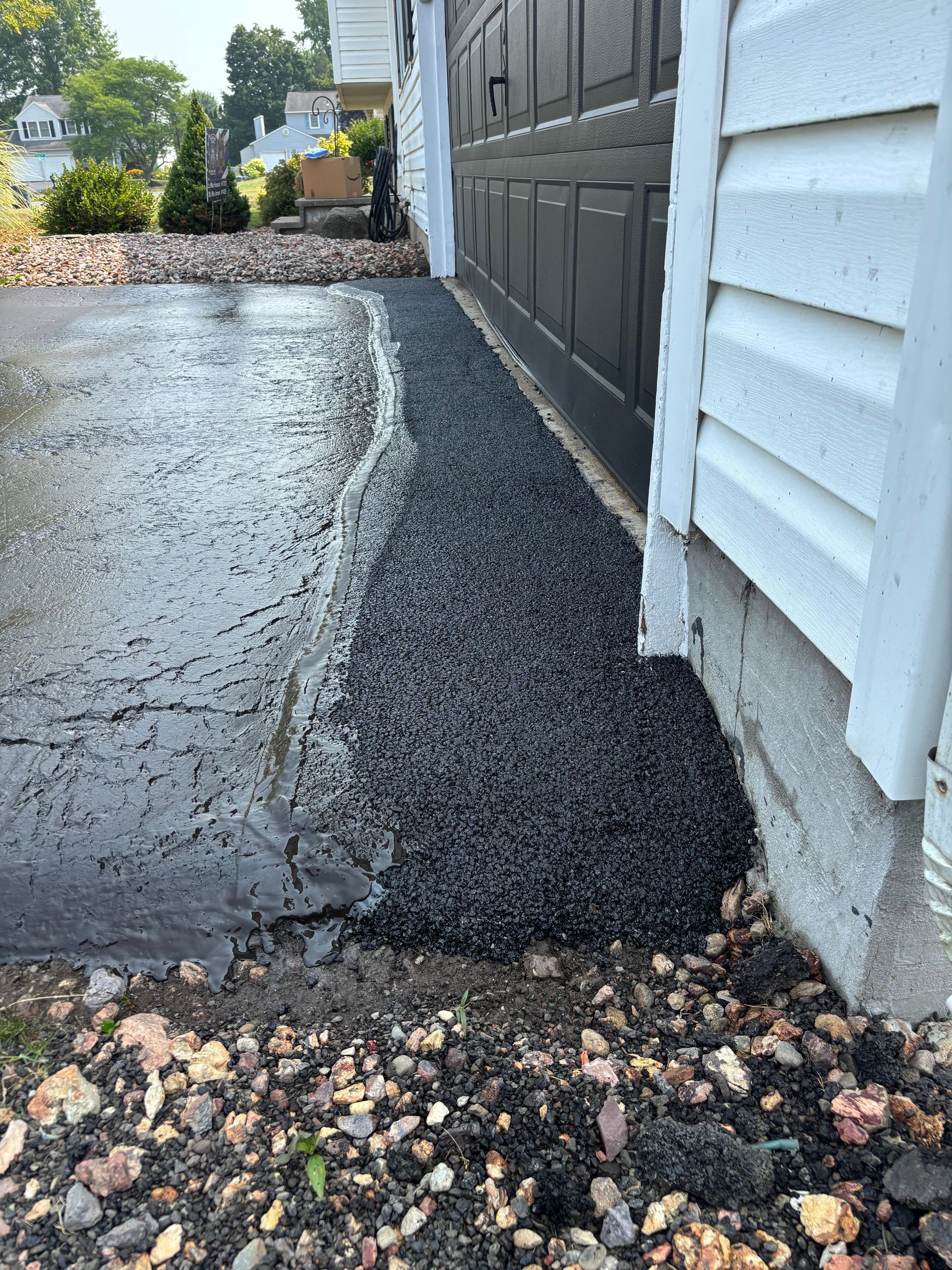 A man is spreading asphalt on the side of a road.