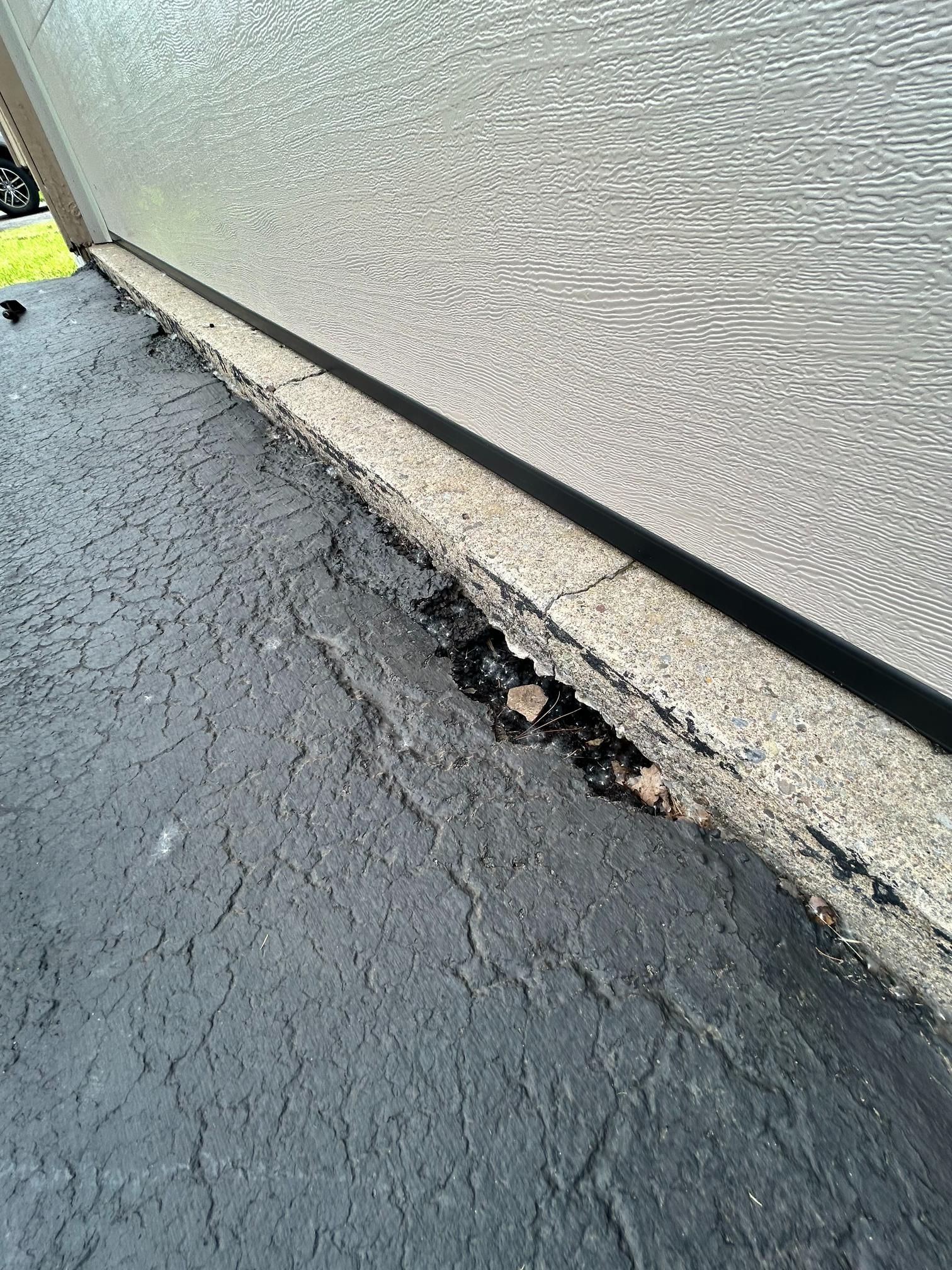 A close up of a concrete curb next to a garage door.
