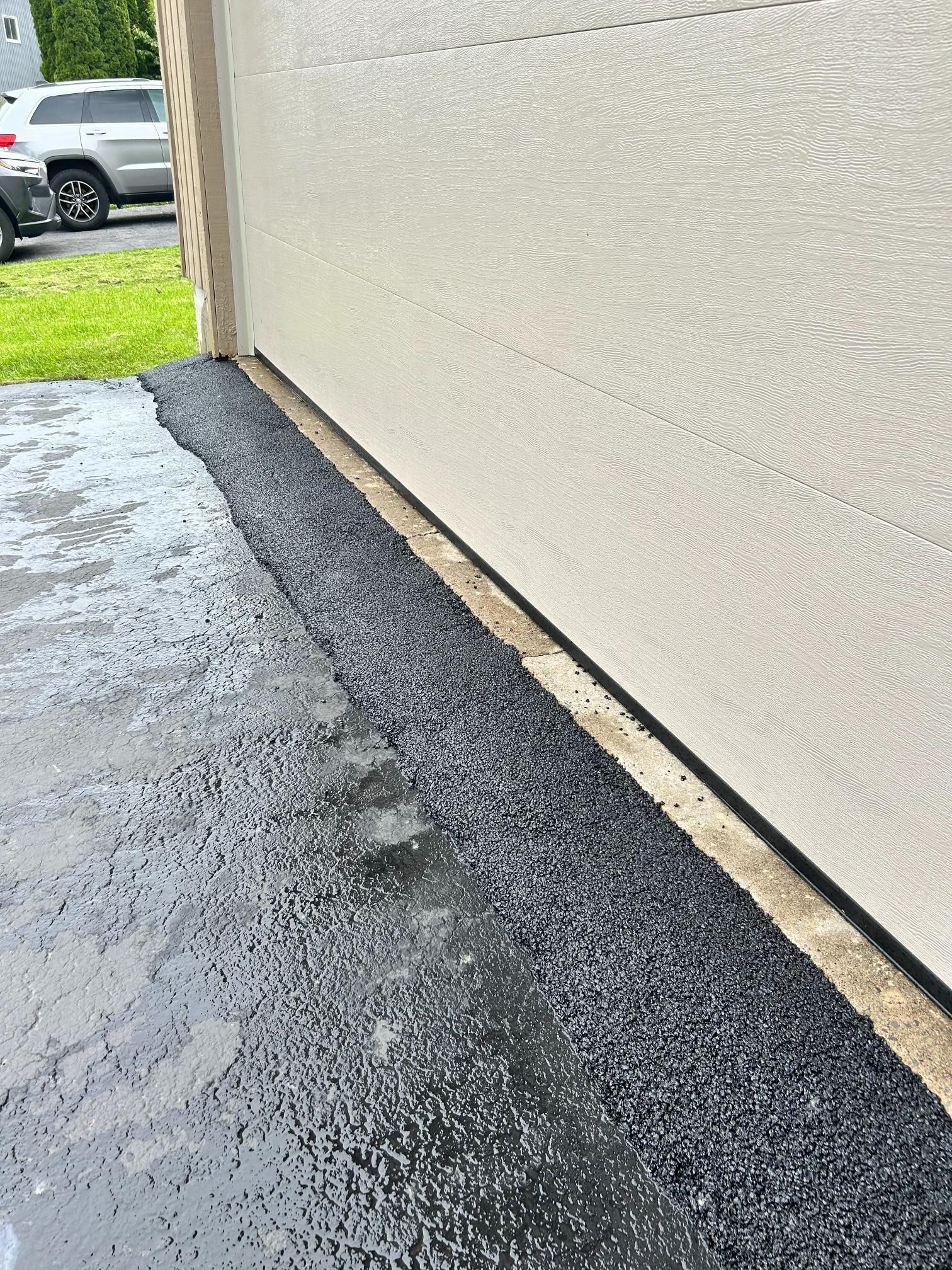 A car is parked in a driveway next to a garage door.