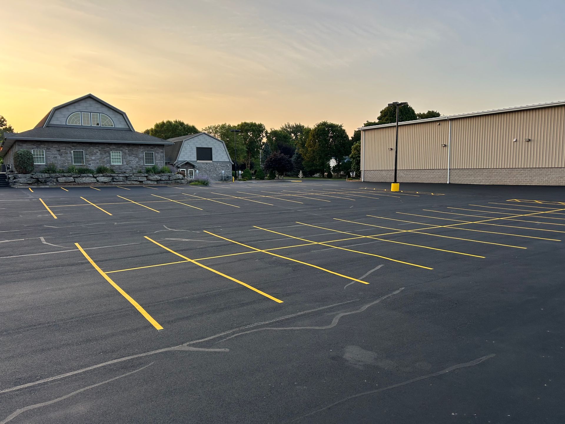 A parking lot with yellow lines and a building in the background