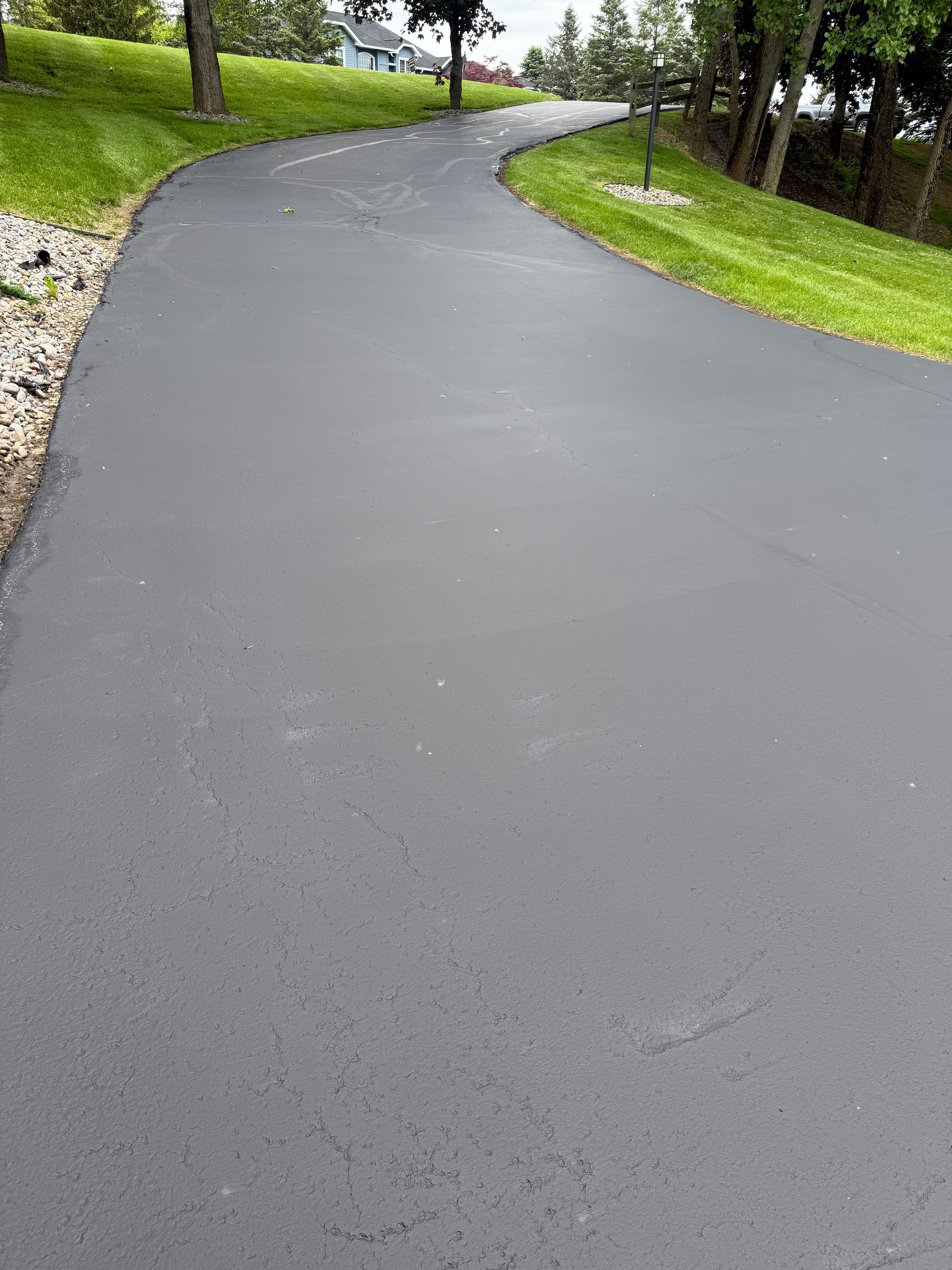 A curvy asphalt driveway going through a grassy area.