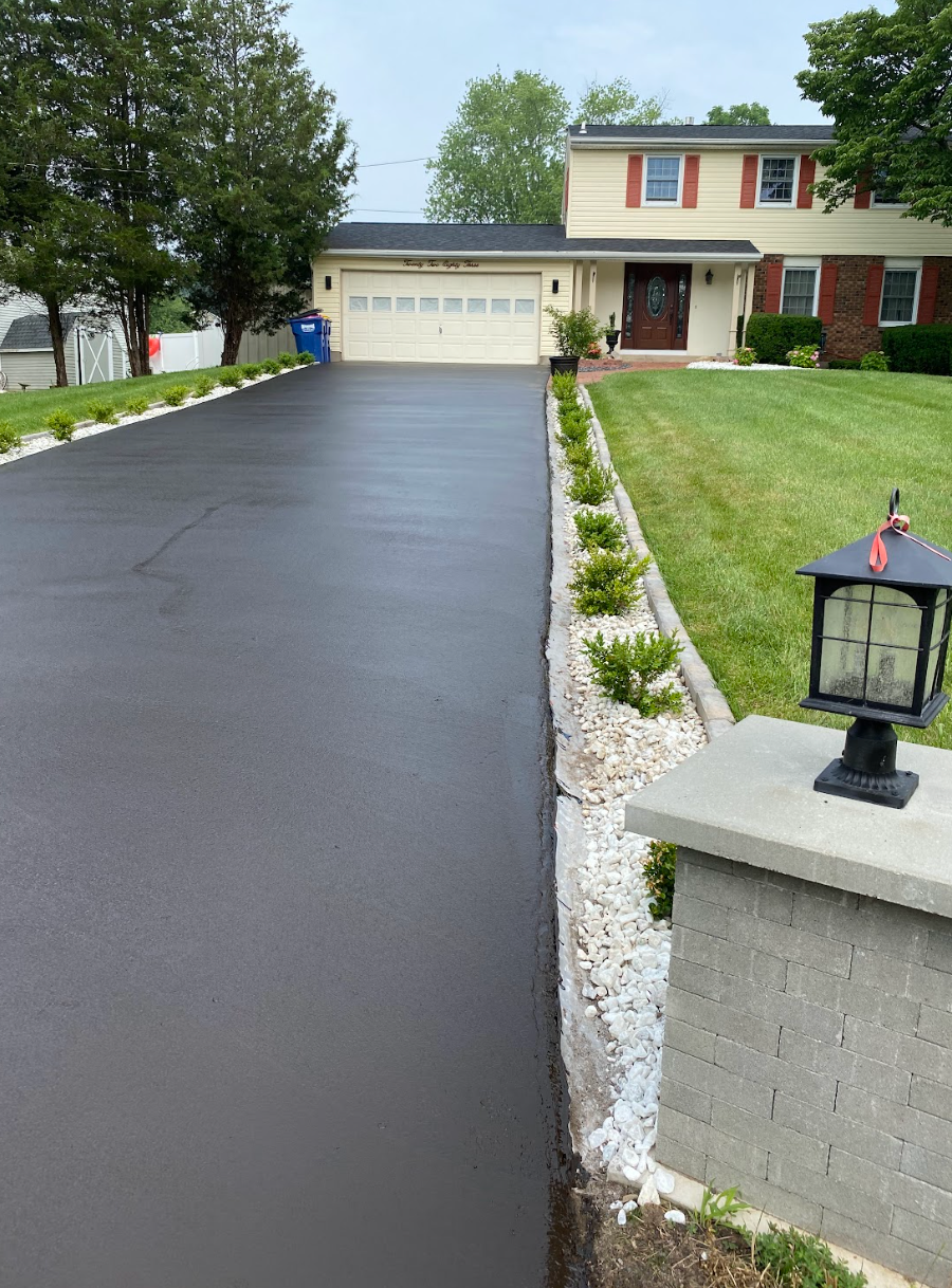A driveway leading to a house with a lantern on the side of it.
