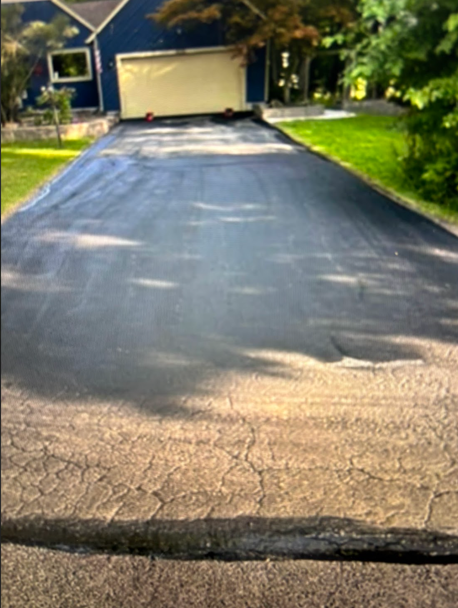 A driveway with a blue house in the background