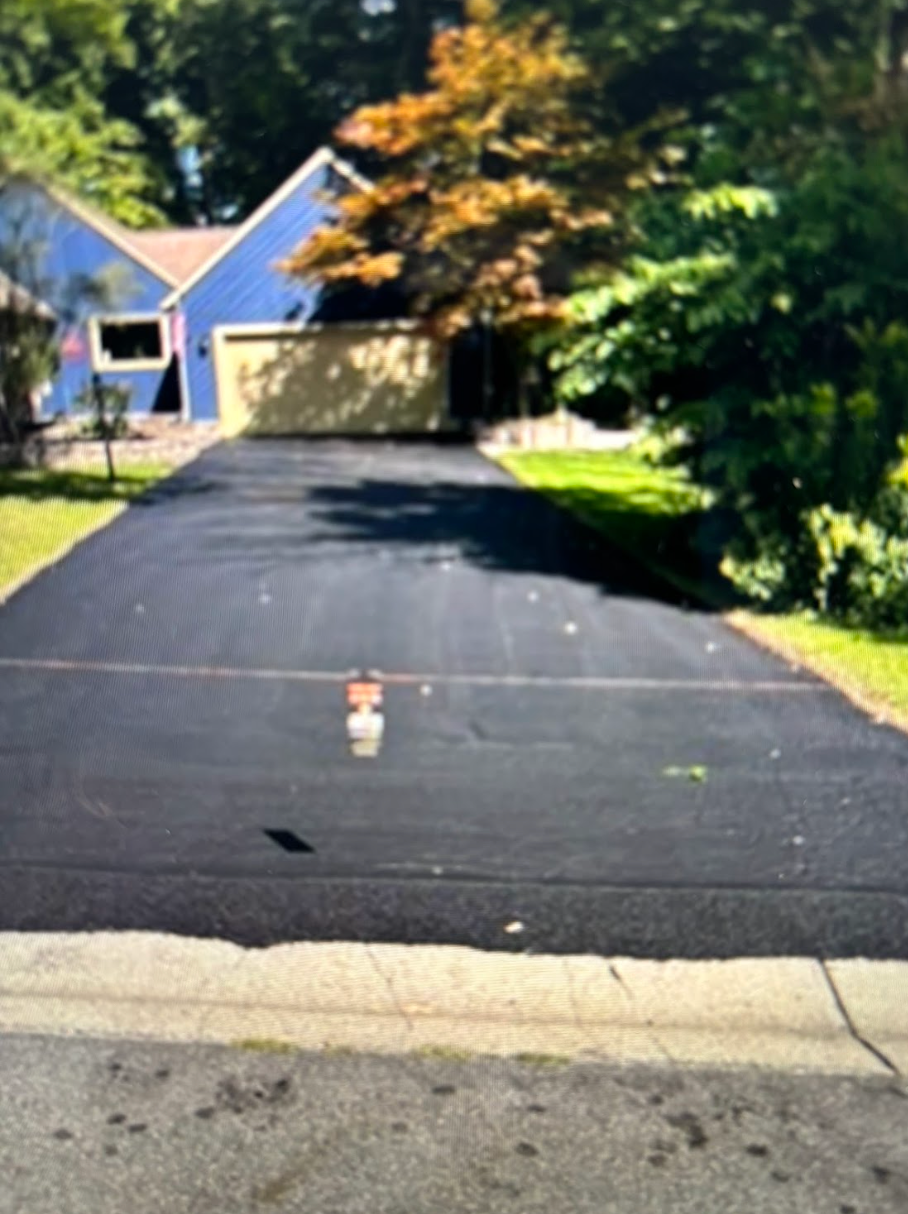 A driveway leading to a house with a blue house in the background