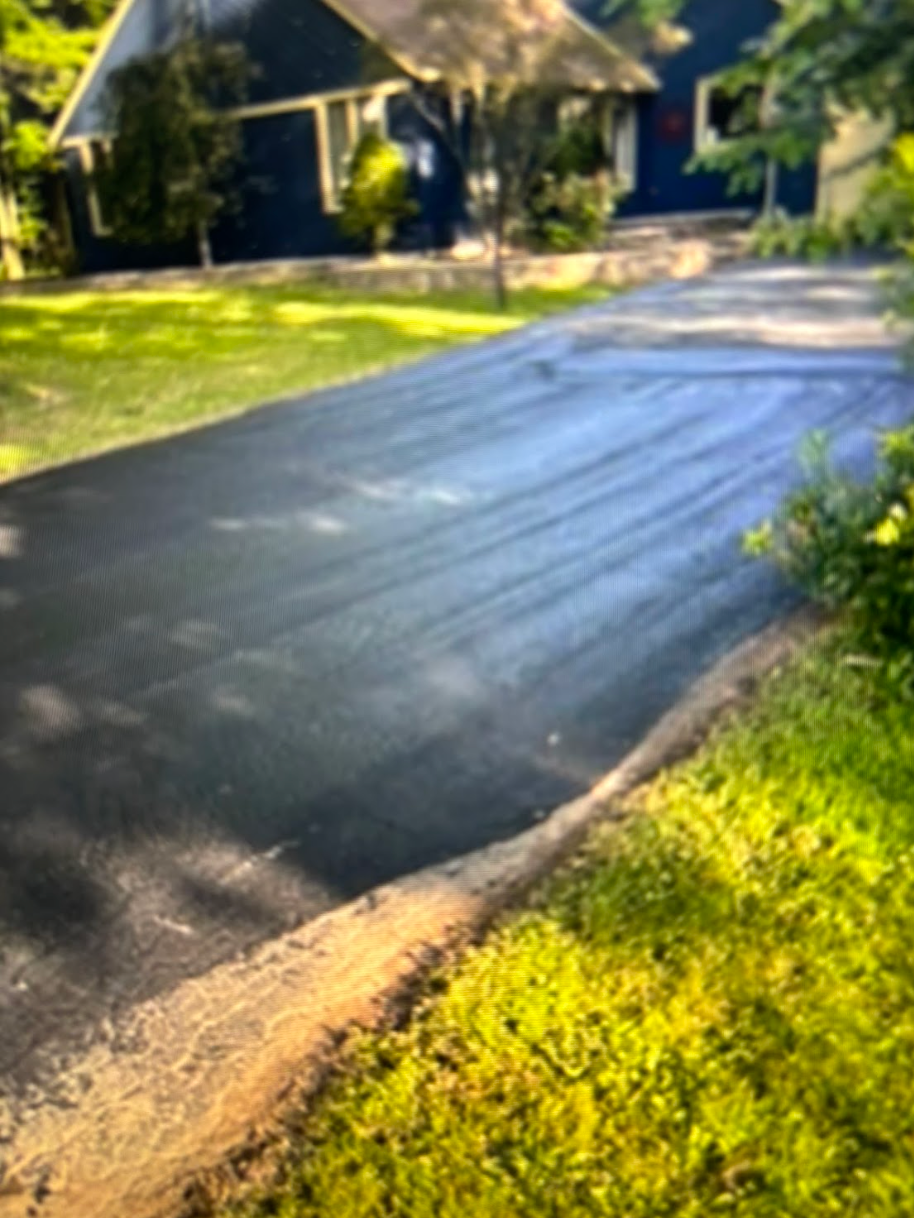 A driveway leading to a house with a blue house in the background.