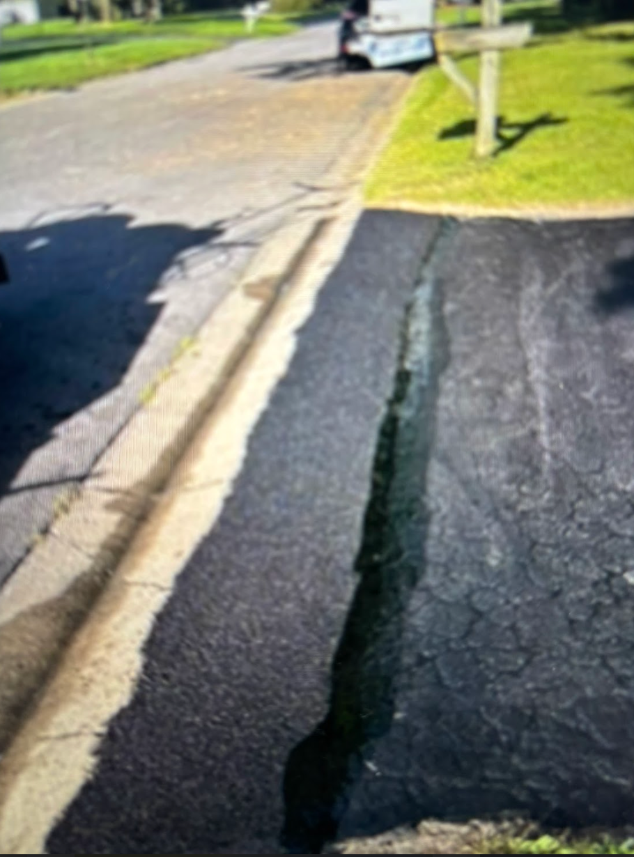 A shadow of a car is cast on a patch of asphalt