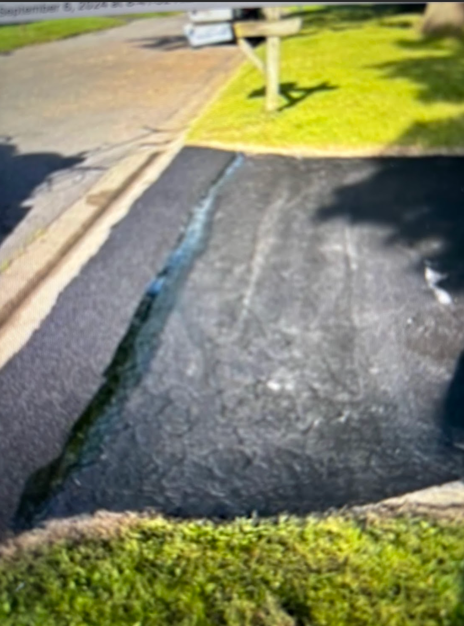 A patch of black asphalt is sitting on the side of a road.