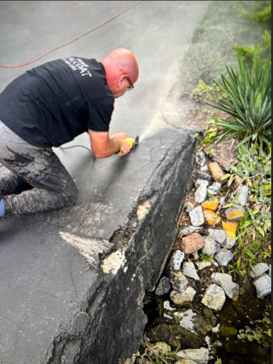 A man is kneeling down next to a large rock.