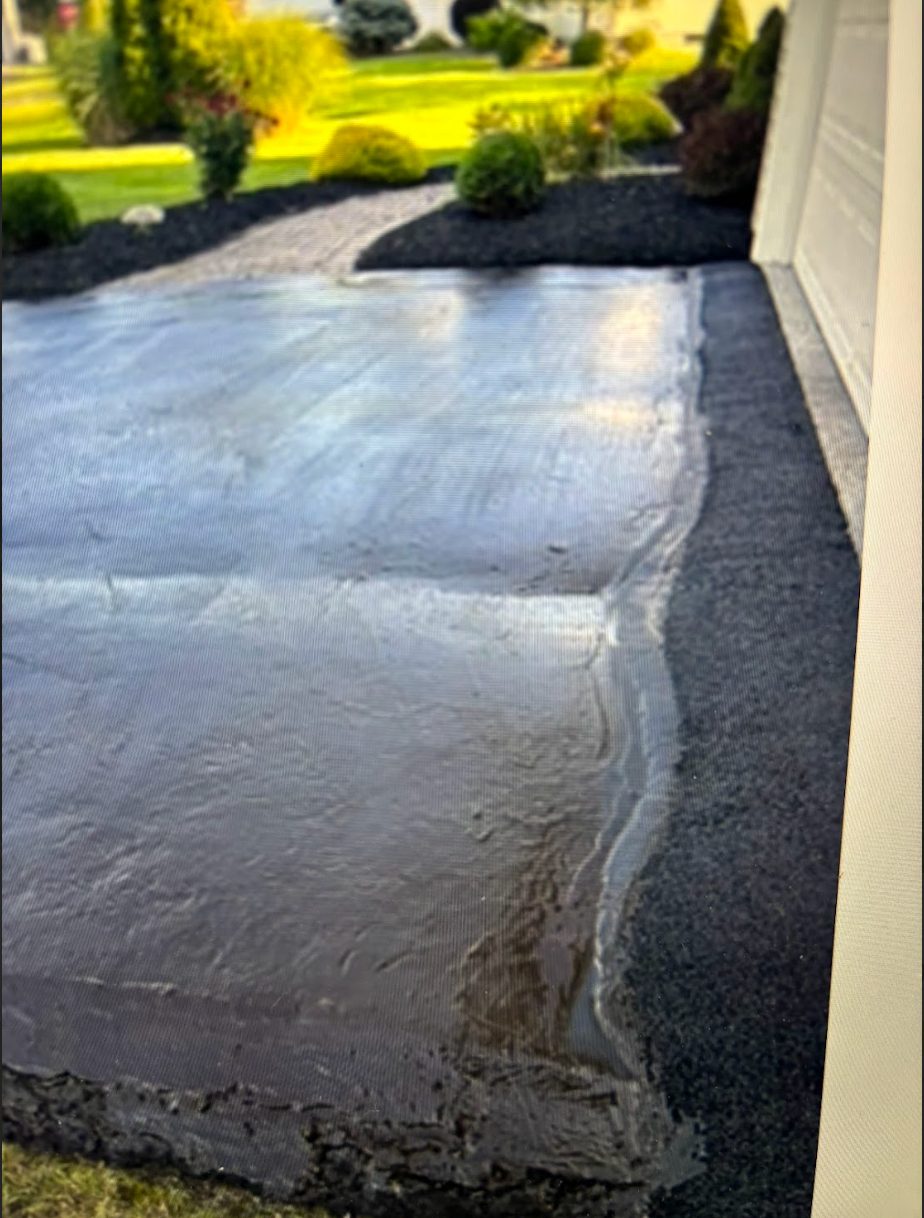 A concrete driveway is being built in front of a house.
