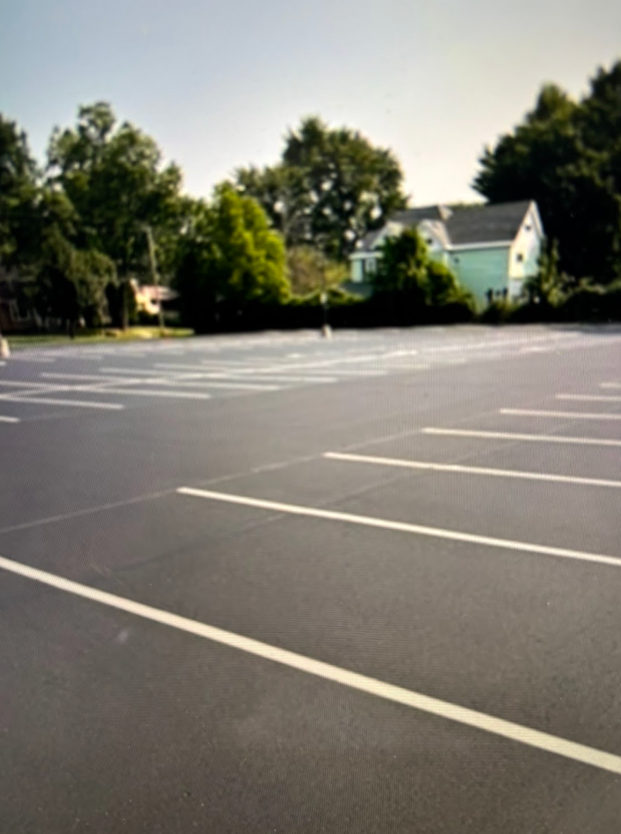 An empty parking lot with a house in the background