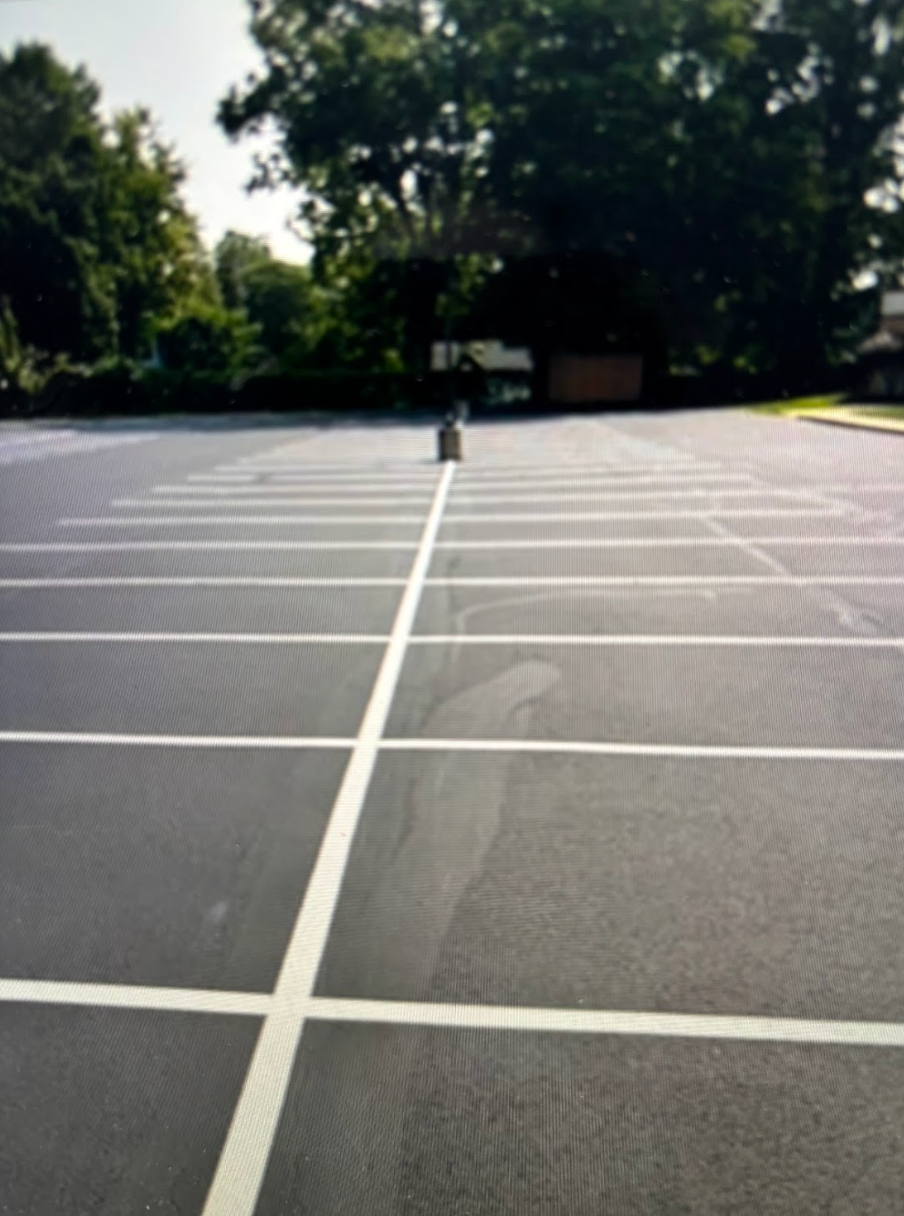 A parking lot with white lines and trees in the background