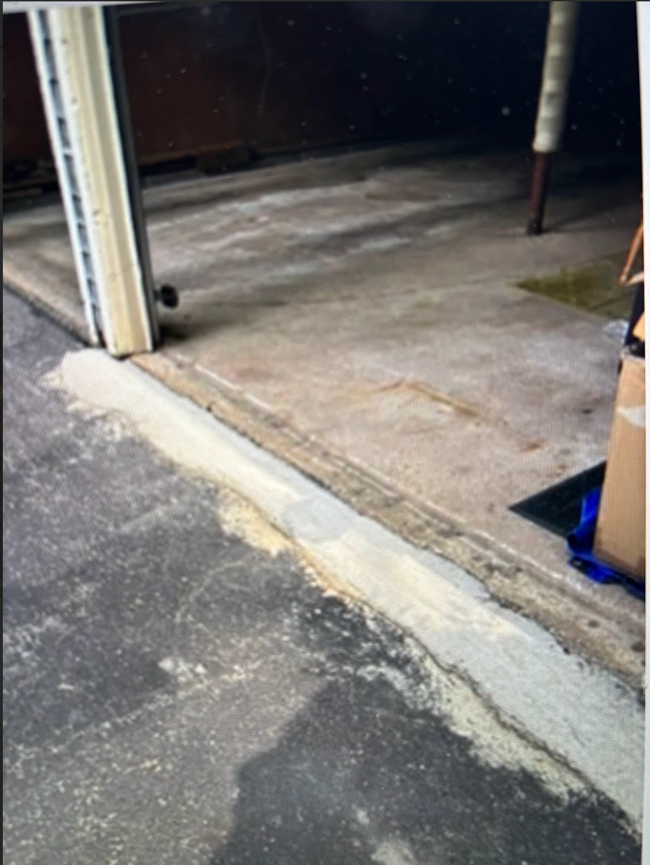 A picture of a garage door with a concrete curb