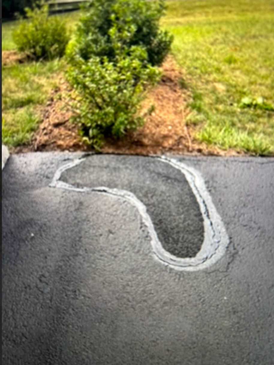 There is a hole in the asphalt in the shape of a heart.