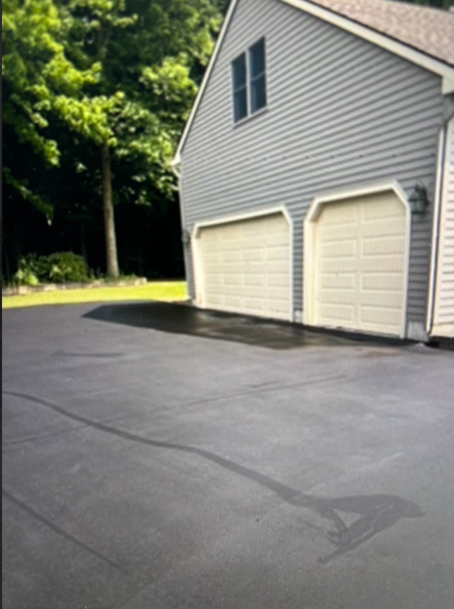 A garage with two garage doors and a driveway in front of it